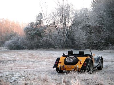 The yellow Plus 8, top down, parked in a frosted clearing at dawn